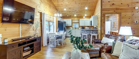 A wooden interior with a TV, dining area, kitchen, and seating.