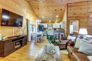 A wooden interior with a TV, dining area, kitchen, and seating. - Hot Tub Haven! Family-friendly Blue Ridge Cabin (Blue Ridge)
