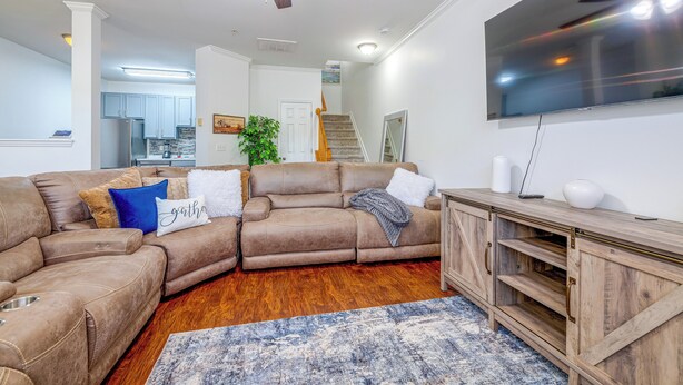 A living room with a sectional sofa, a flat-screen TV, and a wooden entertainment center. - Home Gym & Pool Access! North Raleigh Retreat (Raleigh)