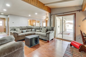 Ein geräumiges Wohnzimmer mit einem Ecksofa, einem kleinen Couchtisch und einer roten Bank.