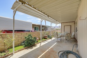 Ein überdachter Patio-Bereich mit Tisch und Stühlen, einer Ziegelwand und Kübelpflanzen.