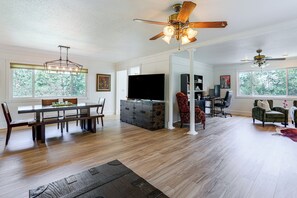A spacious living area with a dining table, chairs, a television, and a ceiling fan. - 1 Mi to Courthouse Plaza! Home w/ Deck + Fireplace (Prescott)