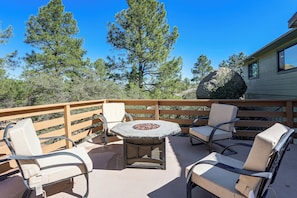 A patio with outdoor seating, a fire pit, and a view of surrounding trees and a house. - 1 Mi to Courthouse Plaza! Home w/ Deck + Fireplace (Prescott)