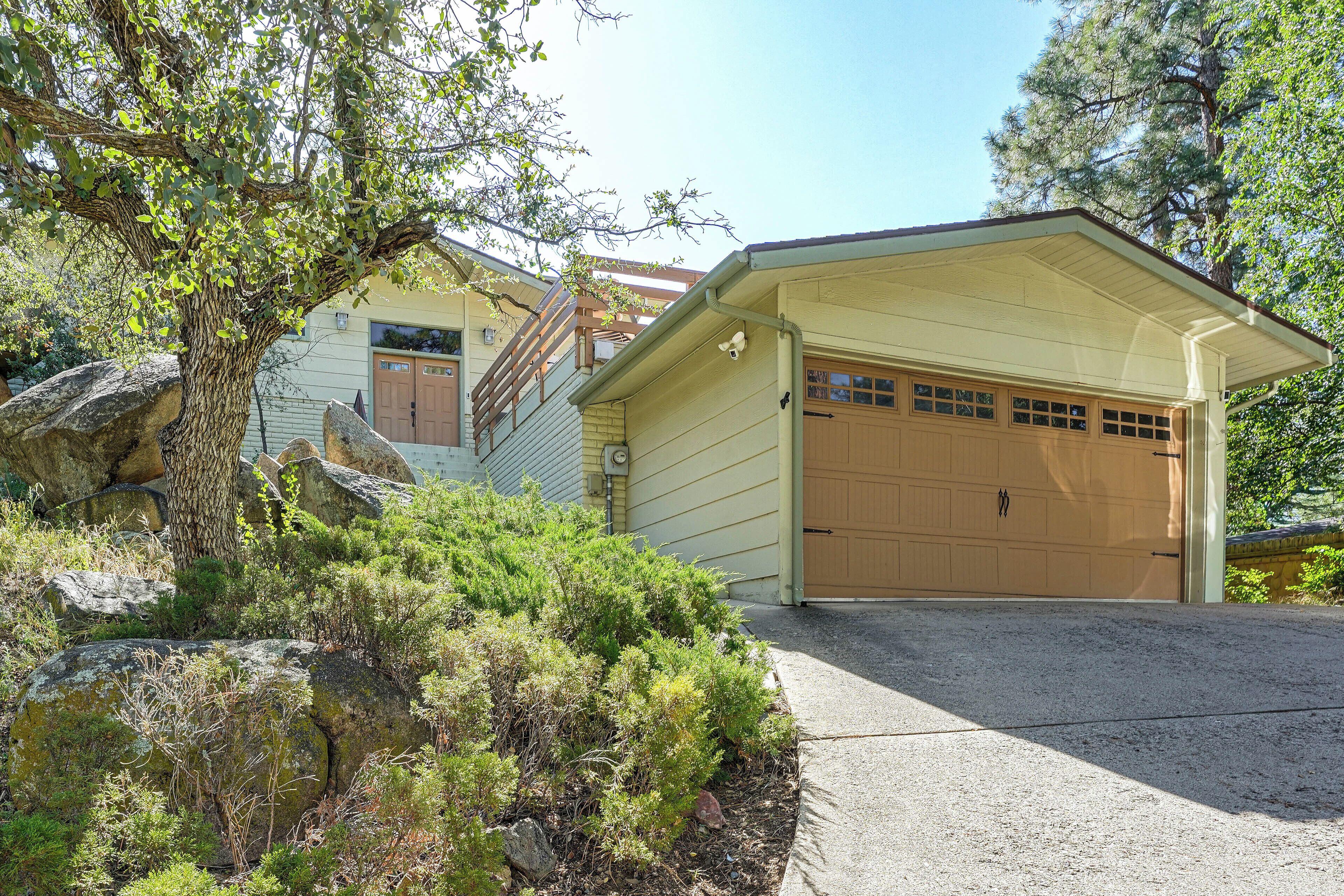 A two-story house with a garage, surrounded by natural landscape and trees.