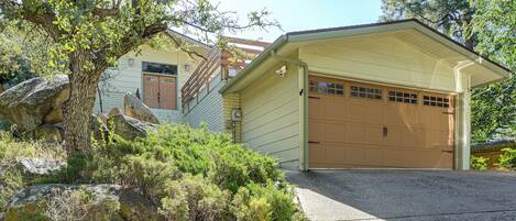 A two-story house with a garage, surrounded by natural landscape and trees.