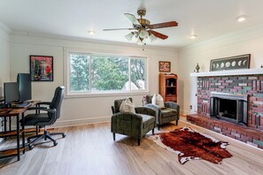 A living room with a fireplace, a desk with a computer, and a large window. - 1 Mi to Courthouse Plaza! Home w/ Deck + Fireplace (Prescott)