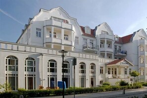 Ein mehrstöckiges Hotel mit Balkonen, Bogenfenstern und einem überdachten Eingang.