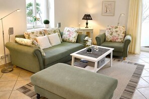 Ein Wohnzimmer mit einem grünen Sofagarnitur, einem Couchtisch und einer Lampe.