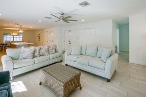 A spacious living room with two light-colored sofas, a woven coffee table, and a ceiling fan. - 3 Mins to Beach! Poolside Paradise in Siesta Key (Siesta Key)