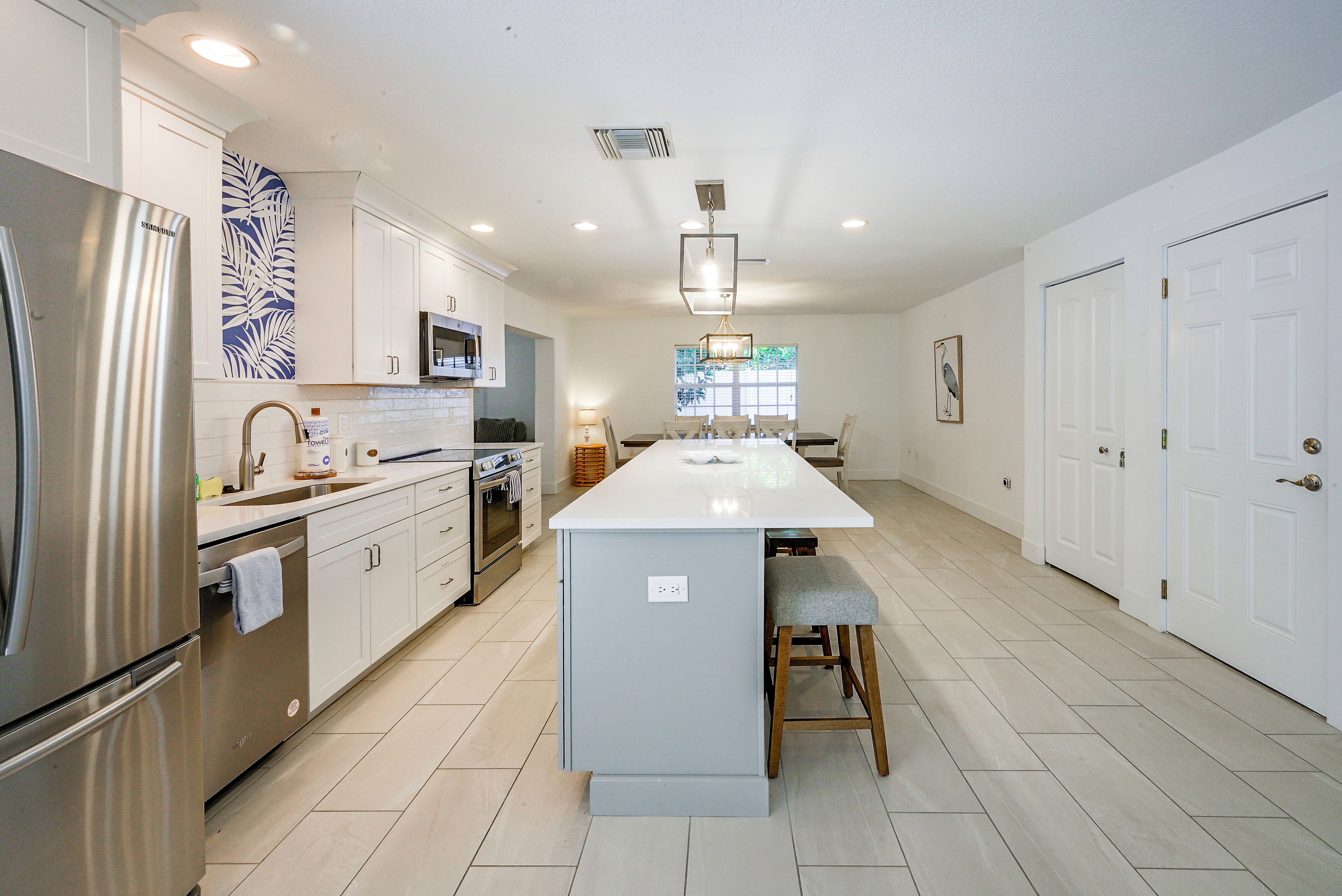 A modern kitchen with stainless steel appliances, a central island, and a dining area with a view.