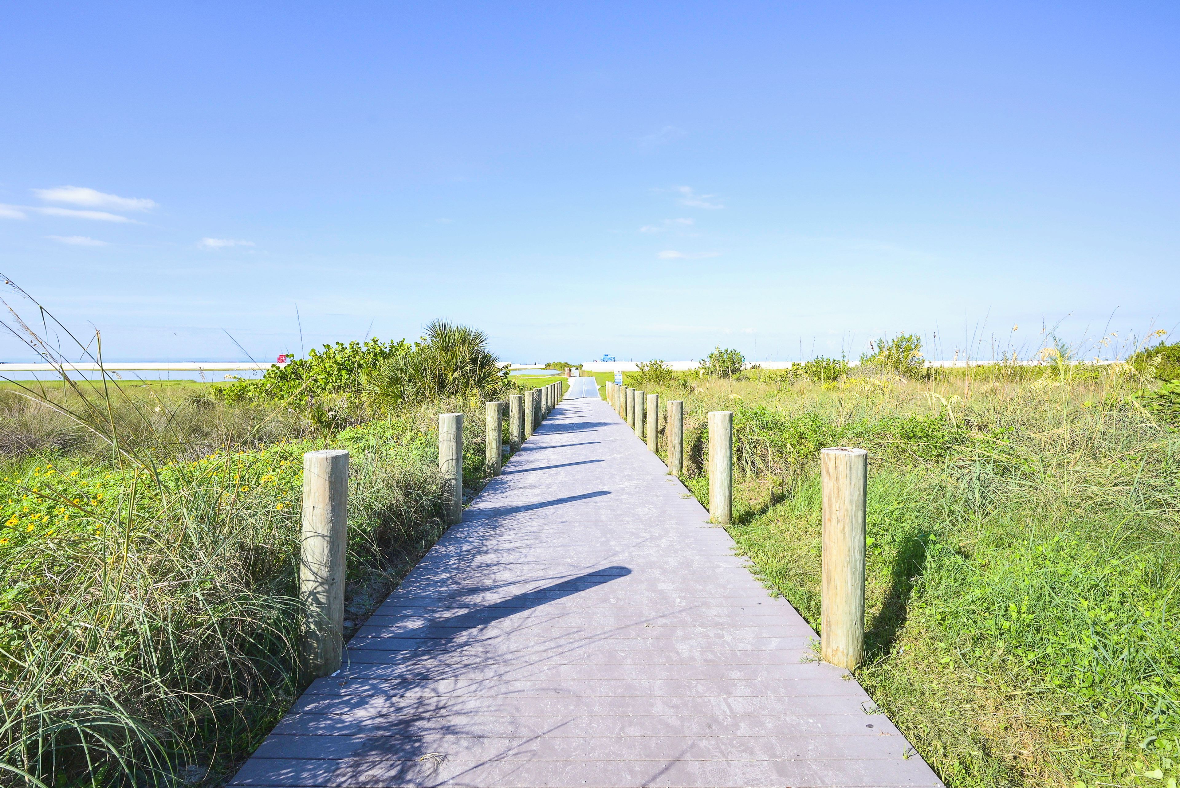 A concrete pathway bordered by wooden posts, leading towards a body of water.