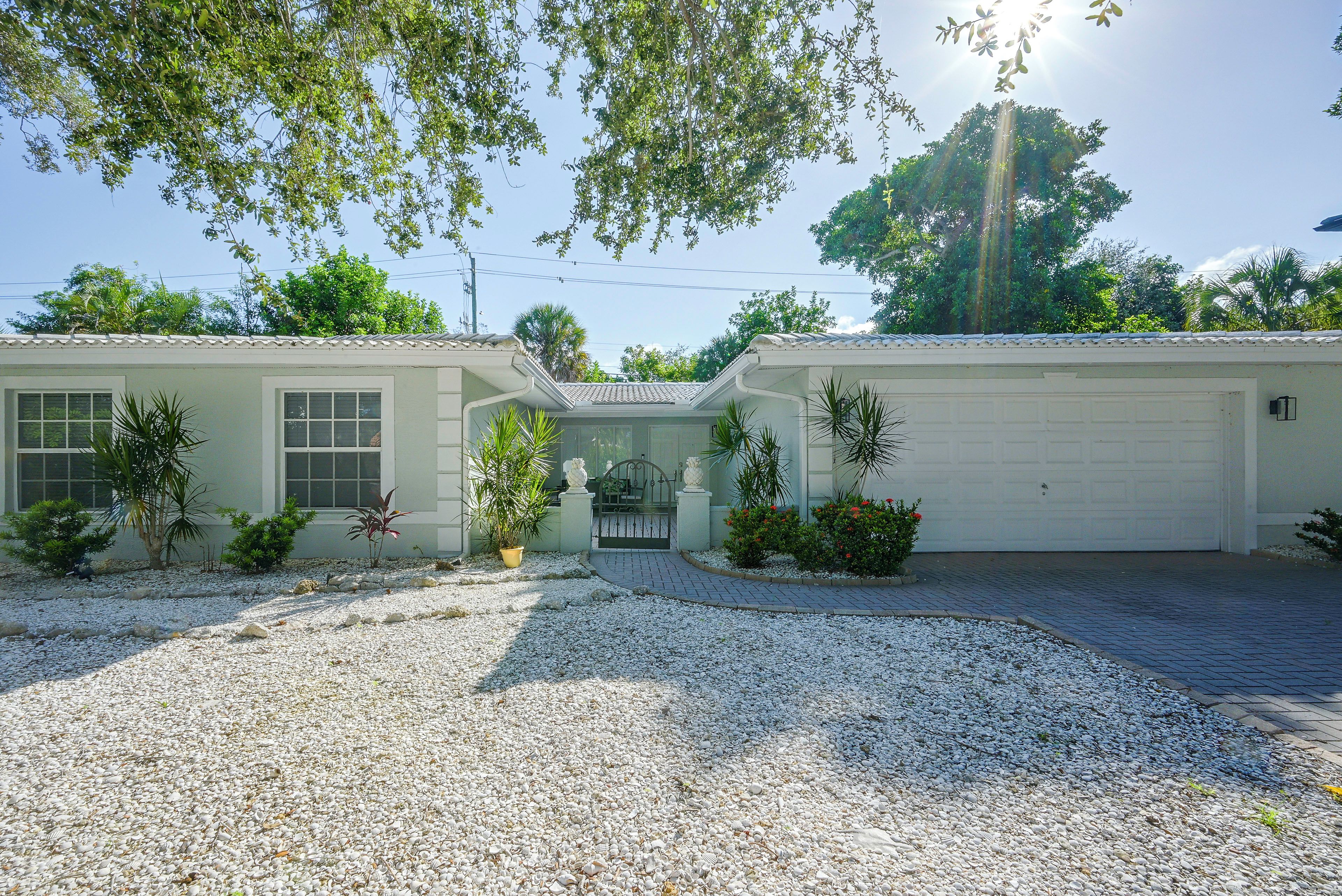 A single-story house with a garage, surrounded by gravel and small plants.