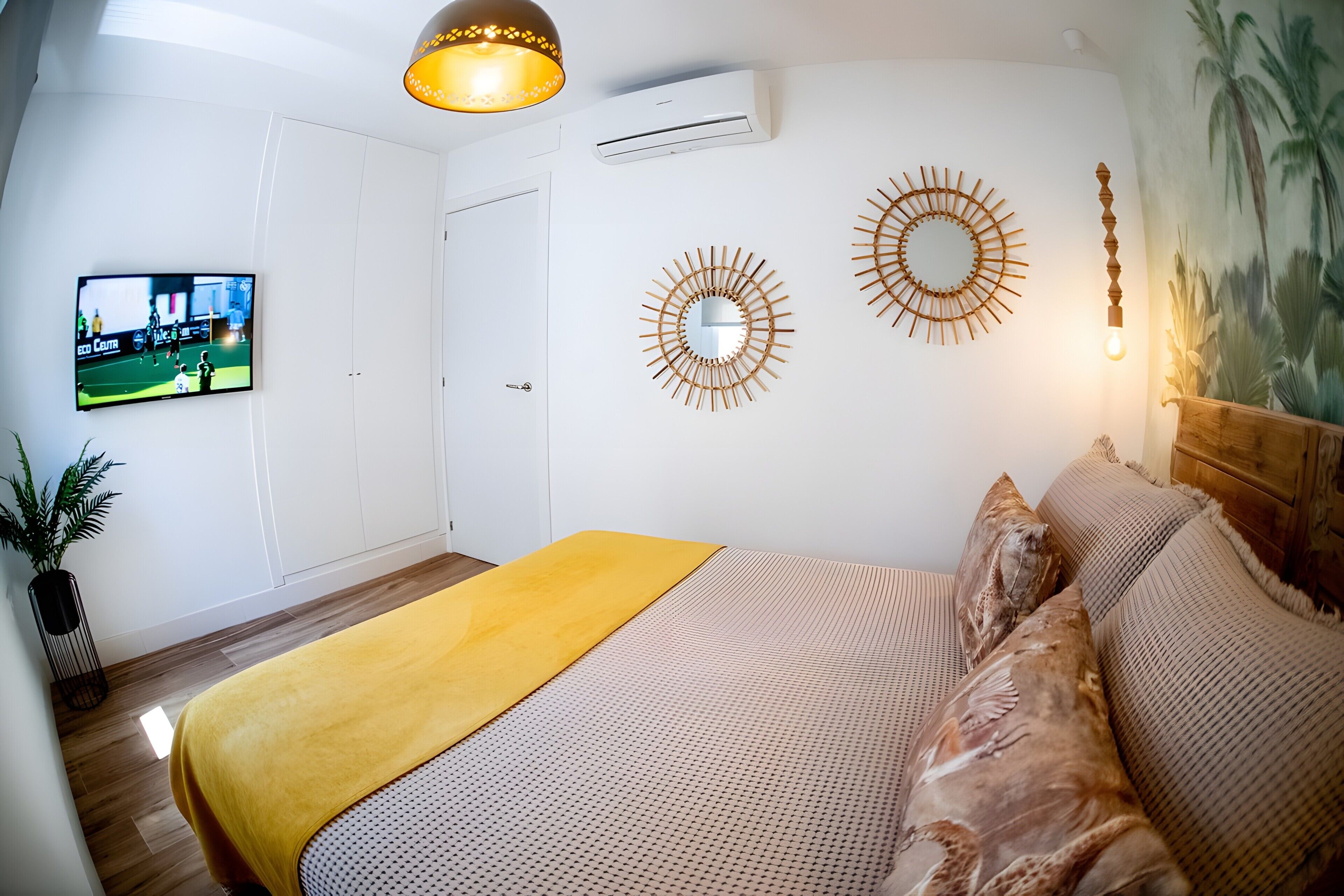 Une chambre à coucher avec un lit, un téléviseur fixé au mur et des œuvres d’art décoratives.