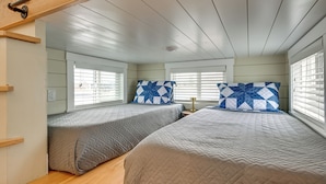 Quarto com duas camas, cada uma com colcha acolchoada e travesseiro estampado.