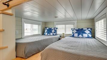 Un dormitorio con dos camas, cada una con una colcha acolchada y un cojín estampado.