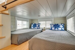 Een slaapkamer met twee bedden, elk met een gewatteerde spreidek en een gestreept kussen.