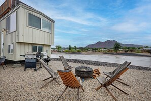 A modern house with a patio area featuring outdoor furniture, a grill, and a fire pit.