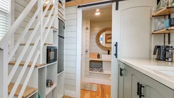 A kitchen with white cabinetry, a wooden staircase, and a kitchen island with a coffee maker.