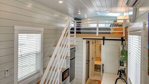 Um interior compacto e moderno com beliche, eletrodomésticos embutidos e armário com porta deslizante.