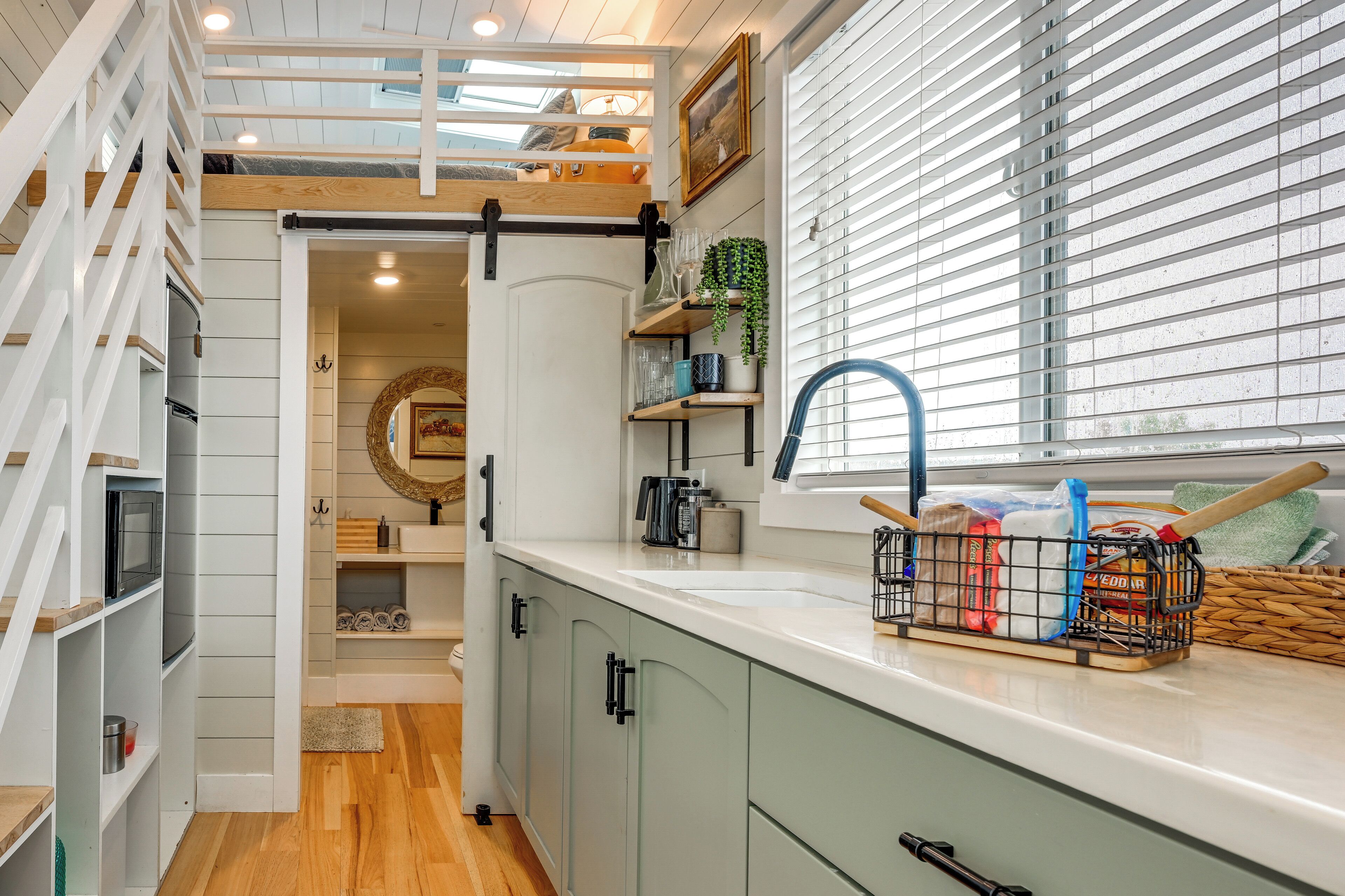A modern kitchen with a built-in microwave, a sink, and a window with blinds.