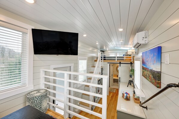 A modern interior with a flat-screen TV, a staircase, and a kitchen area.