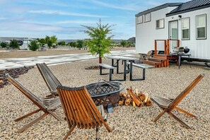 An outdoor seating area with a fire pit, benches, and a grill.