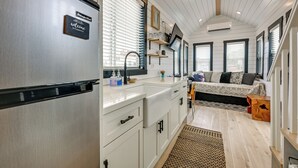 Cocina compacta con refrigerador incorporado, lavamanos y encimera con alacenas.