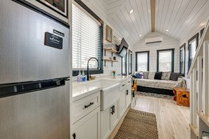 Cocina compacta con refrigerador incorporado, lavamanos y encimera con alacenas.