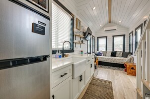 Cocina compacta con refrigerador incorporado, lavamanos y encimera con alacenas.