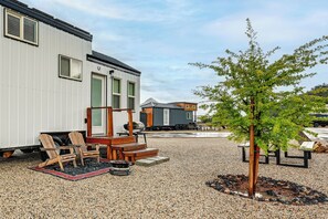 A residential area with a house, a small deck with chairs, and a tree.