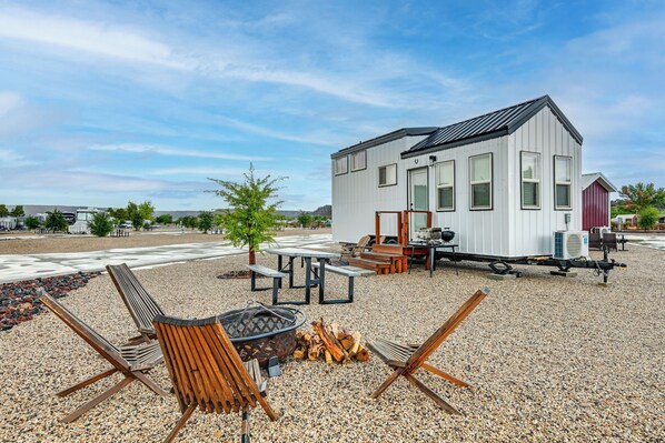 A modern mobile home with a deck, outdoor seating, and a fire pit. - Gateway to Red Rock Adventures! Resort Tiny Home (Hurricane)