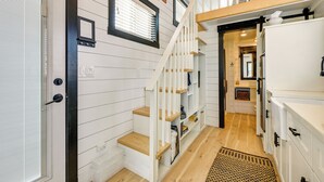 Una escalera con barandales blancos y escalones de madera que sube a un segundo piso.