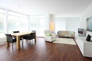 A modern living room with a dining table, sofa, and TV. - Holiday apartment at the marina 319704 (Kühlungsborn)