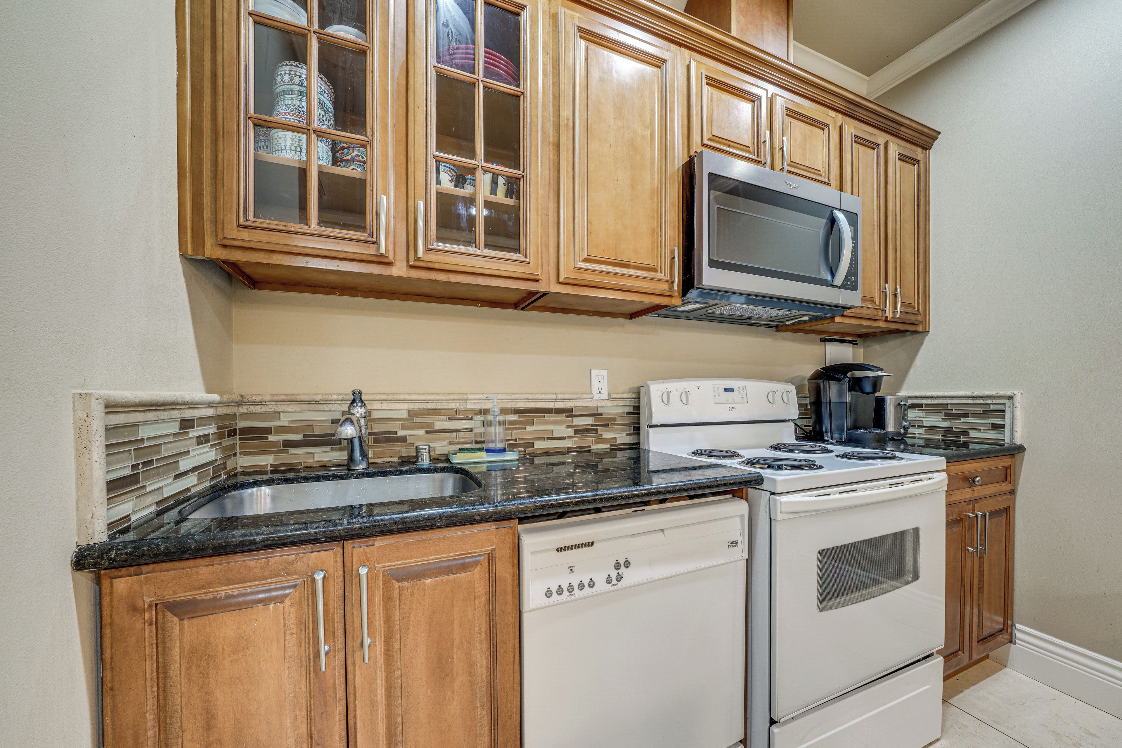 A kitchen with wooden cabinets, a microwave, a stove, and a dishwasher.