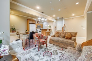 A spacious living room with a patterned sofa, a floral armchair, and a dining area with a table and chairs. - Full Kitchen & Laundry! Kirkland Studio Suite (Kirkland)