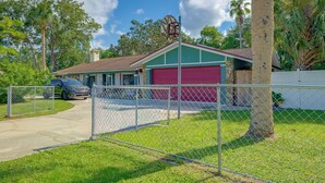 Um imóvel residencial com entrada cercada, garagem e uma casa com porta de garagem vermelha.