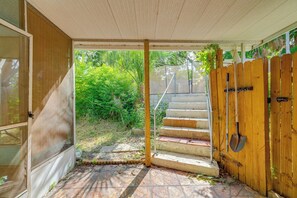 A covered outdoor area with a wooden fence, a metal gate, and a concrete staircase leading to a garden. - 4 Mi to Hudson Beach! Spacious Group Retreat (Hudson)