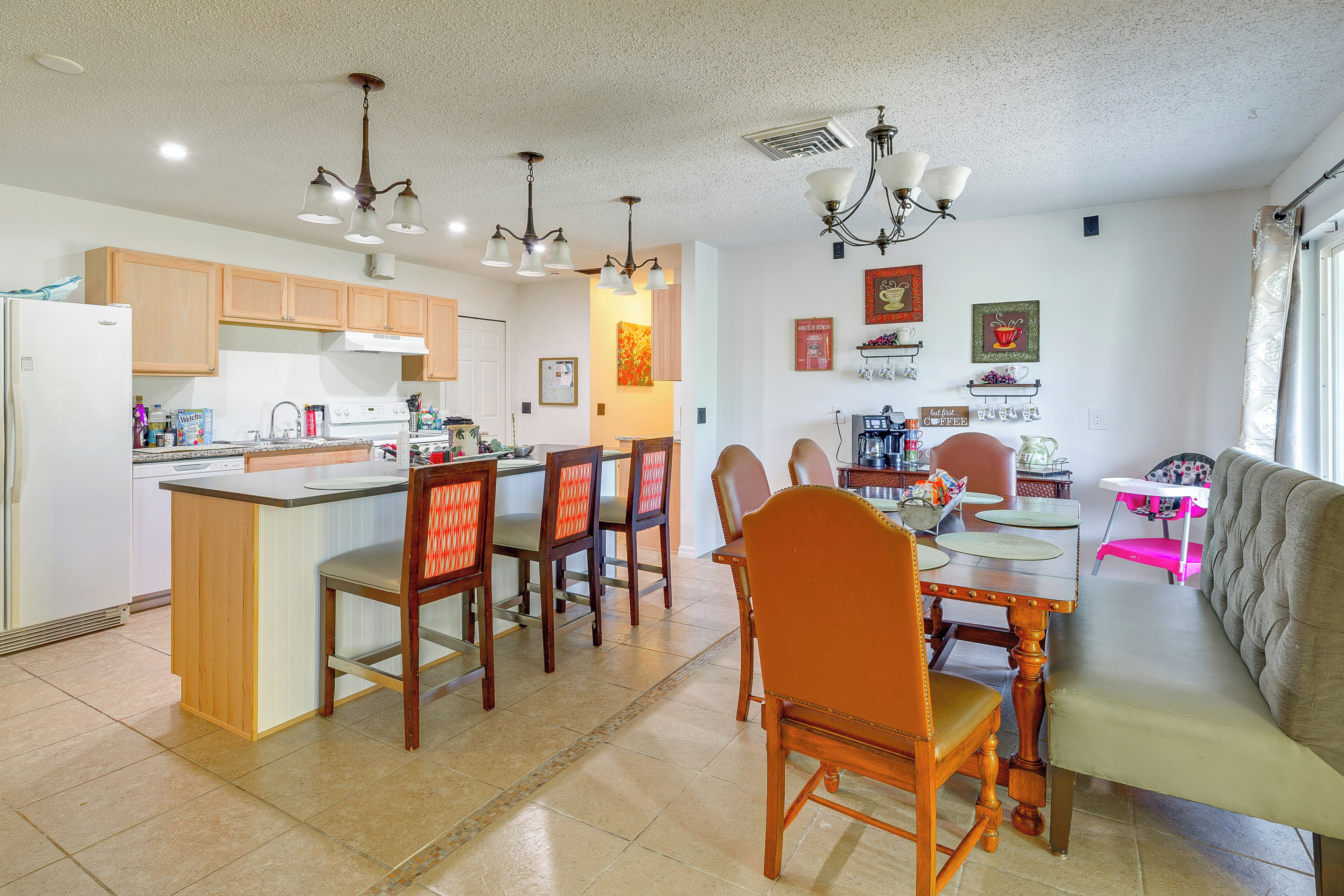 Cozinha moderna com armários de madeira, espaço de refeições com mesa e cadeiras, e sala de estar com sofá.
