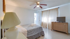 Quarto com cama, penteadeira, ventilador de teto e luminária.