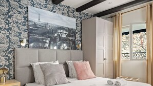 A bedroom with a bed, pillows, a nightstand, a wall-mounted picture, and a wardrobe. - Charmante maison au cœur de Paris – Face au Louvre • 2 personnes (Paris)