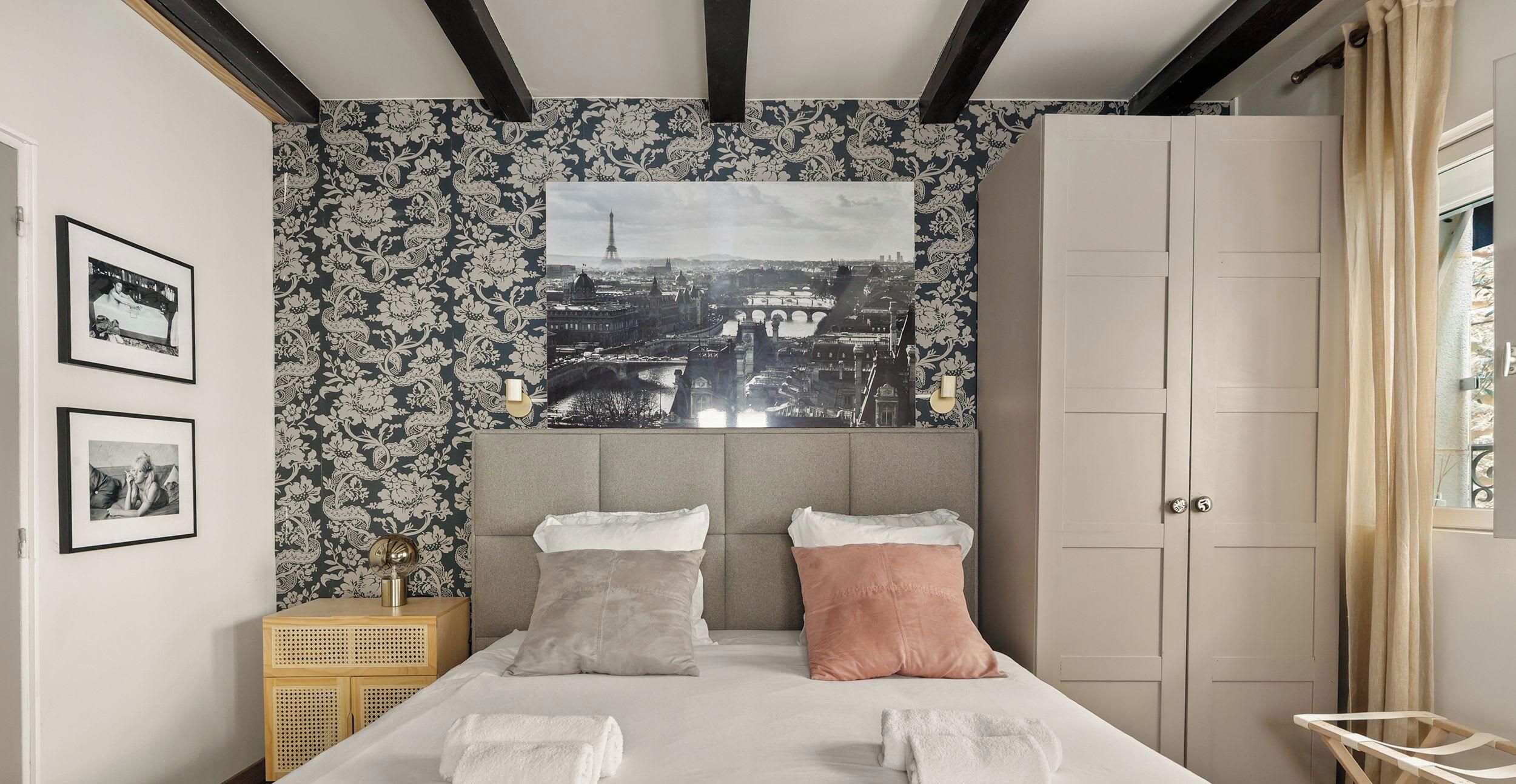 A bedroom with a bed, two pillows, a nightstand, a wall-mounted picture, and a door.