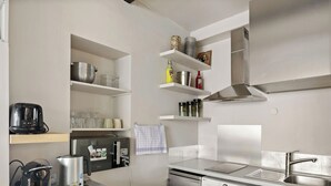 A modern kitchen with a built-in dishwasher, a kettle, and a coffee maker. - Charmante maison au cœur de Paris – Face au Louvre • 2 personnes (Paris)