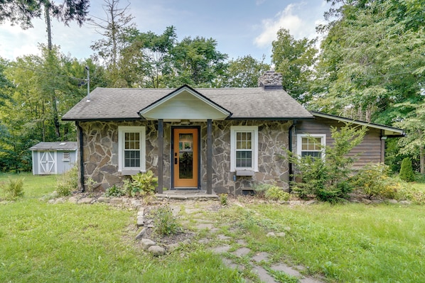 A stone house with a gabled roof, a front door, and a small porch.