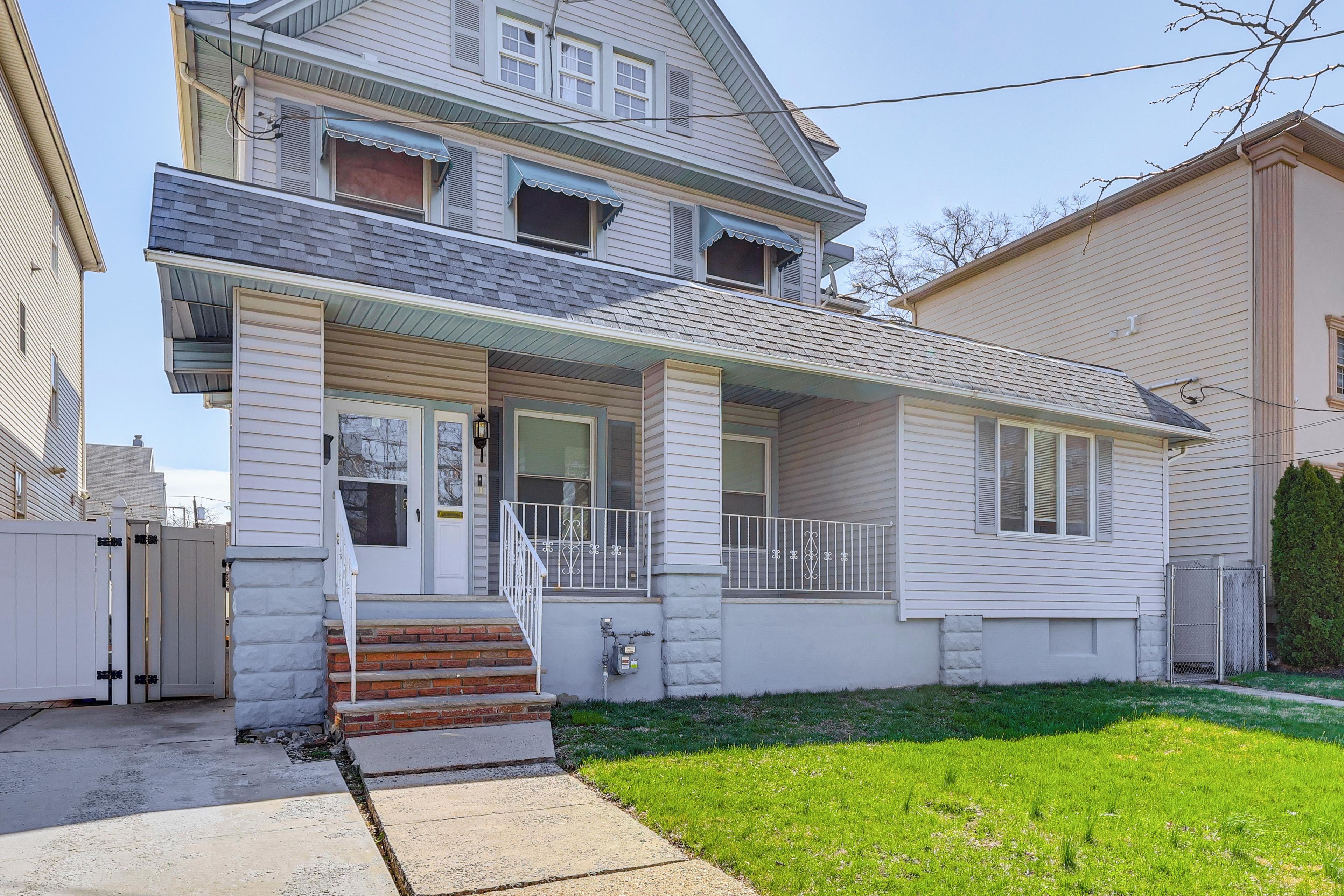 A two-story house with a front porch, a small front yard, and a garage.