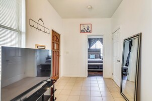 Un pasillo con una cama, una puerta, un perchero y un reloj en la pared.