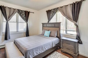 Un dormitorio con cama, mesita de noche y cortinas.