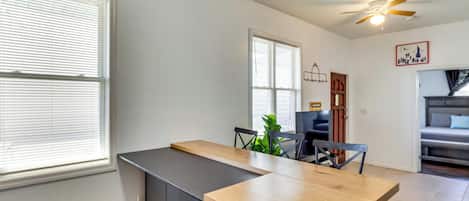 Una cocina moderna con encimera de madera, ventilador de techo y comedor con mesa y sillas.