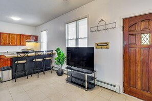 A modern kitchen with a dining area, a flat-screen TV, and a potted plant.