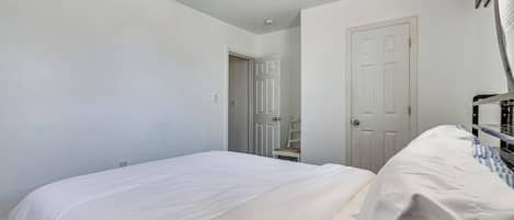 A bedroom with a bed, a ceiling fan, a door, and a window.