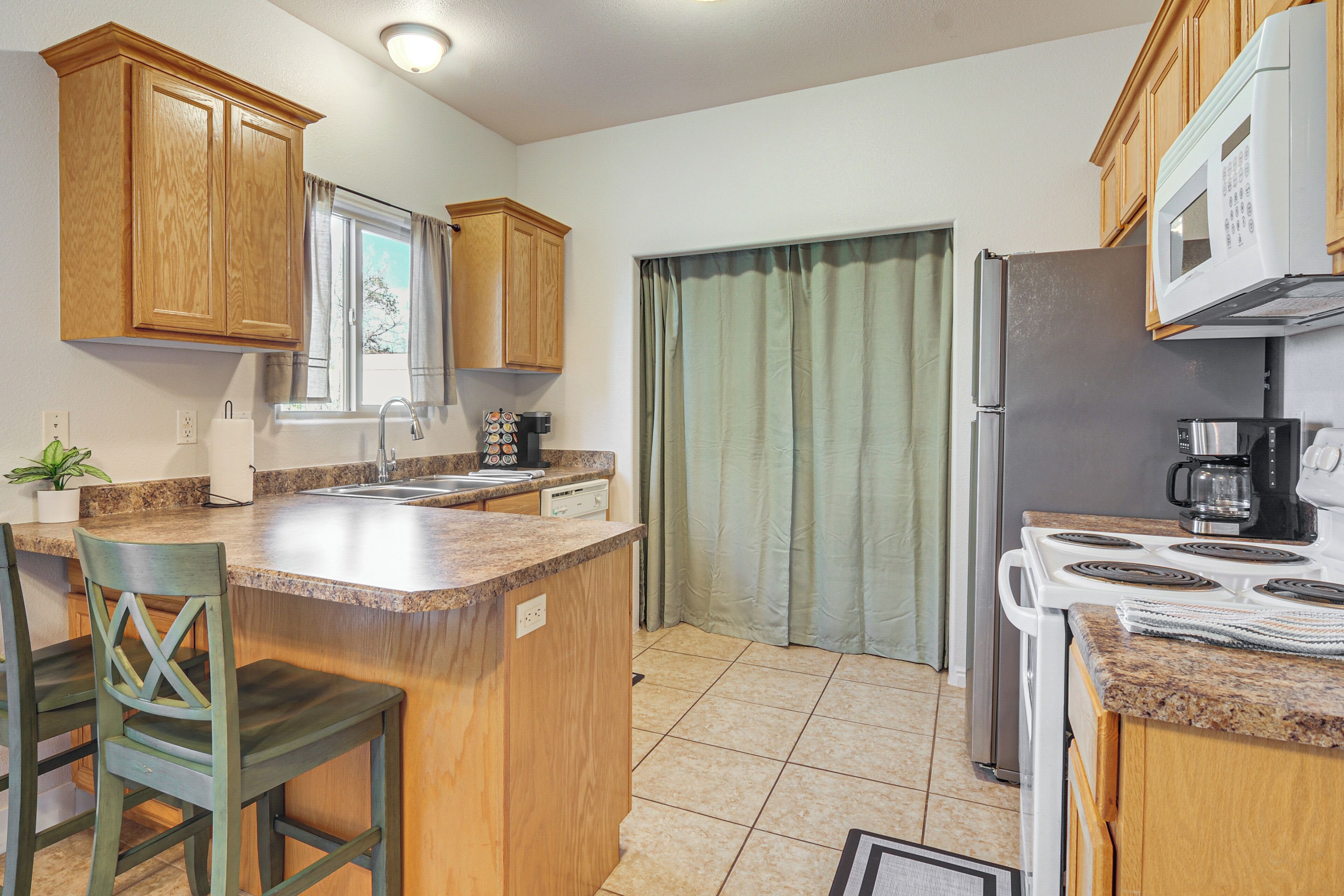 A kitchen with wooden cabinets, a granite countertop, a sink, a stove, and a refrigerator.